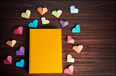 Yellow book surrounded by paper hearts