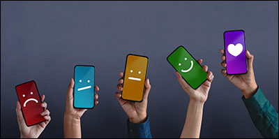 Five hands holding a smartphone, each. Faces are drawn on them and they get progressively happier; the last phone shows a heart.