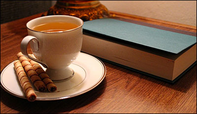 a cup of tea, cookies, and a book