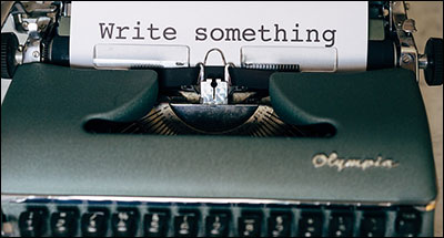 typewriter with page that says "write something"