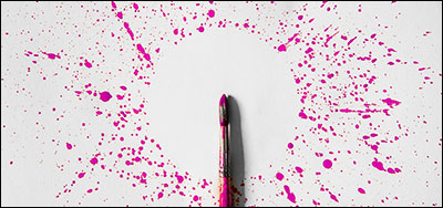 paintbrush surrounded by pink paint splatters